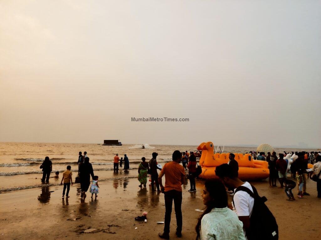 Families walking on Juhu Beach at dusk